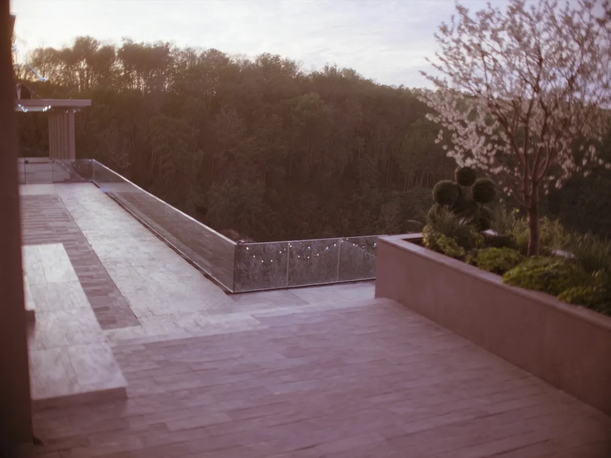 Elevated stone terrace with glass railings near the Scarborough Bluffs — interlocking pavers and built-in planters at dusk